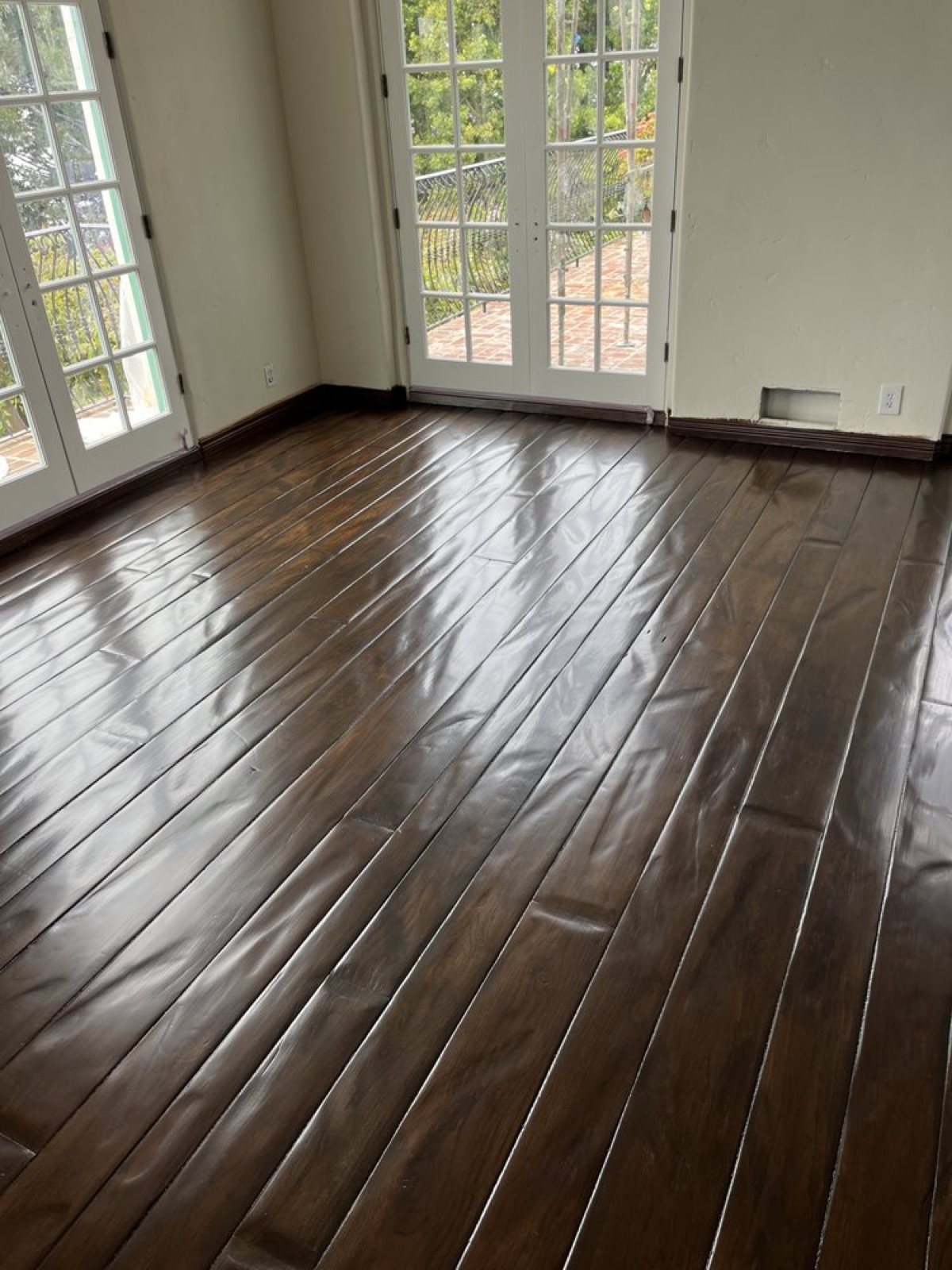 Dark walnut-stained plank floor with a deep gloss finish by french doors